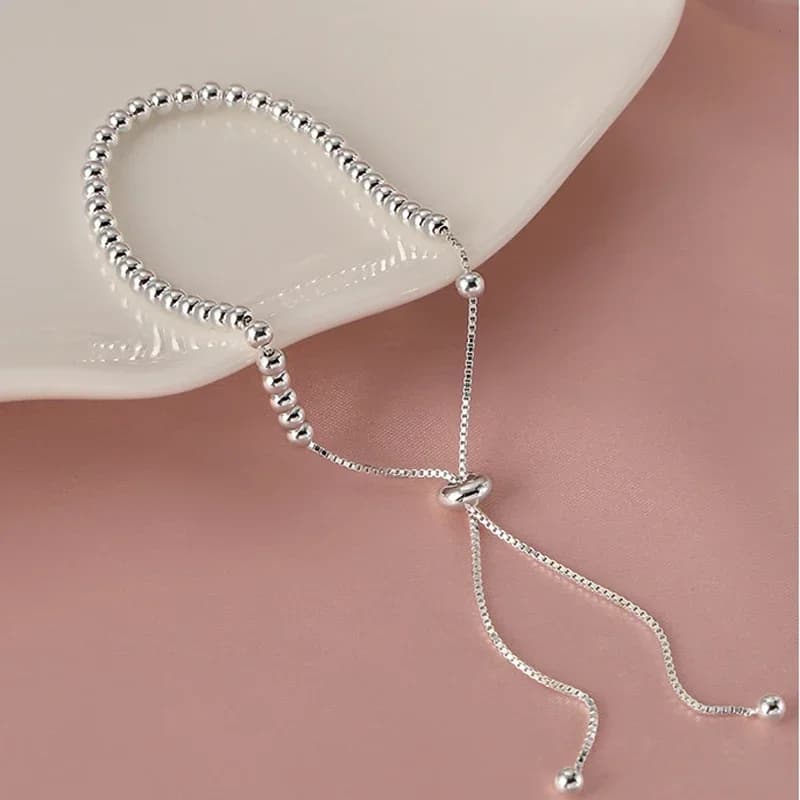 The bead bracelet held up showing the adjustable sliding cord mechanism and how it drapes
