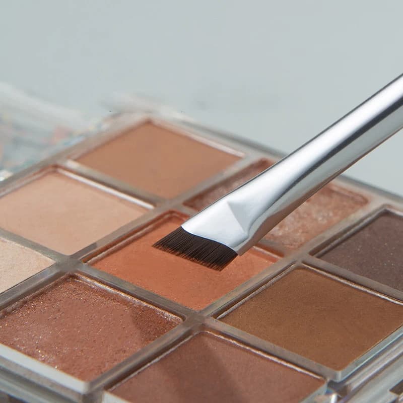 Angled makeup brush with protective cap showing compact size