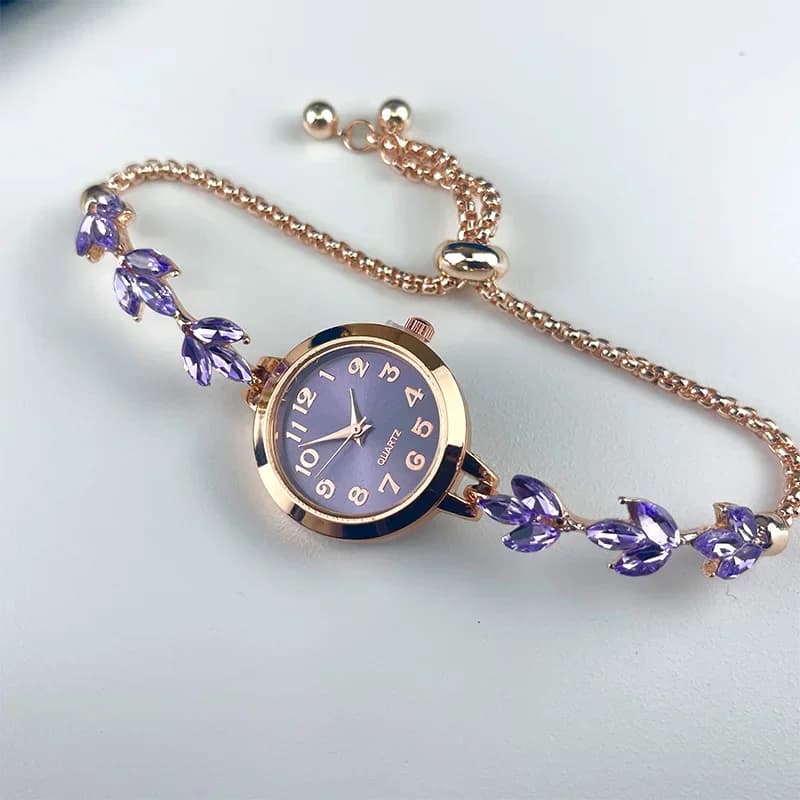 Elegant women's rhinestone bracelet watch with a gold tone finish and crystal accents laid flat on a white surface